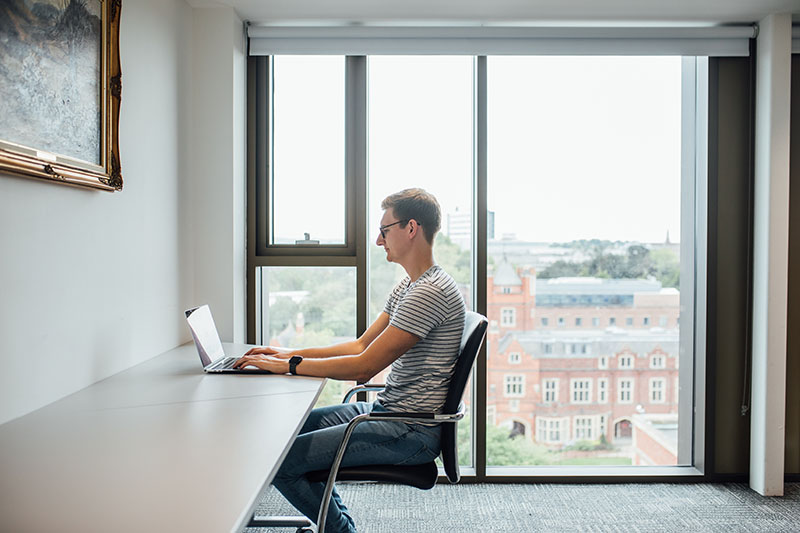 A student using a laptop in the School of Law building